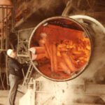 Workers examining heated industrial equipment